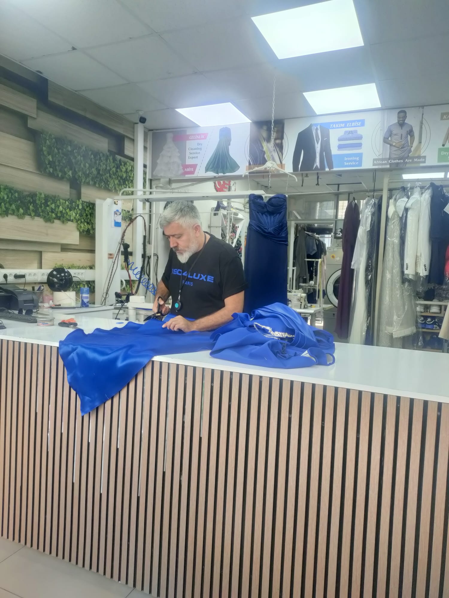Terzi tezgâhında mavi abiye elbisenin tadilatını yapan usta